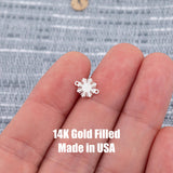 May include: A small, silver-colored charm in the shape of a sunburst. The charm has a series of pointed rays extending outward from a central circular area. Two small loops are on either side of the charm. The text '14K Gold Filled Made in USA' is printed below the charm.