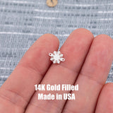 May include: A small, silver-colored charm in the shape of a sunburst. The charm has a series of pointed rays extending outward from a central circular area. Two small loops are on either side of the charm. The text '14K Gold Filled Made in USA' is printed below the charm.