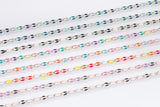 May include: Rows of colorful chain necklaces with gold-colored links. Each chain features a repeating pattern of oval-shaped enamel beads in various colors, including blue, green, purple, pink, orange, red, and black. The necklaces are displayed against a white background.