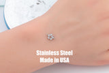 May include: A small, stainless steel hibiscus flower charm with two loops for attaching to jewelry. The charm is shown on a person's skin. Text on the image reads "Stainless Steel Made in USA."